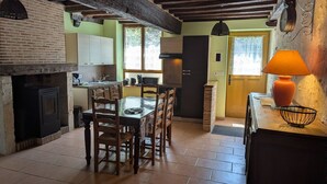Una cocina rústica con chimenea, una mesa de comedor de madera y sillas.
