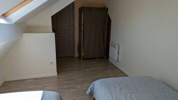Une chambre avec deux lits, un radiateur, une porte et un escalier.