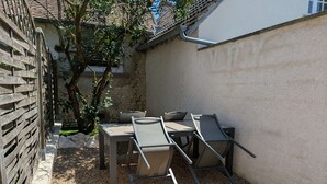 Un patio al aire libre con una mesa, sillas, una valla de madera y un árbol.