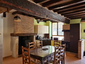 A rustic kitchen with exposed beams, a brick oven, wooden chairs, and a dining table. - Cozy Cottage near Loire Valley Castles & Sologne, Sleeps 4, Private Terrace, Parking Included (Cléry-Saint-André)