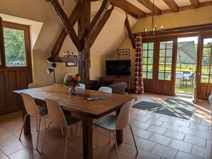 Enjoy meals in this inviting dining area with a rustic table, comfortable chairs, and a large window offering a view of the outdoors.