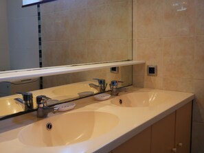 Bathroom features a dual sink vanity with two faucets and a mirror above.