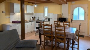 Une cuisine compacte avec des meubles blancs, une table à manger avec des chaises, un canapé et une fenêtre donnant sur un beau paysage.