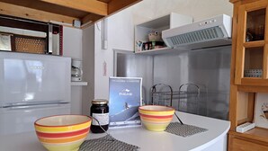 A kitchen with a white countertop, a Beko refrigerator, a coffee machine, and a small cabinet with a microwave.