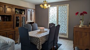 Un comedor con una mesa dispuesta para seis personas, rodeada de sillas, una araña y un aparador con adornos.