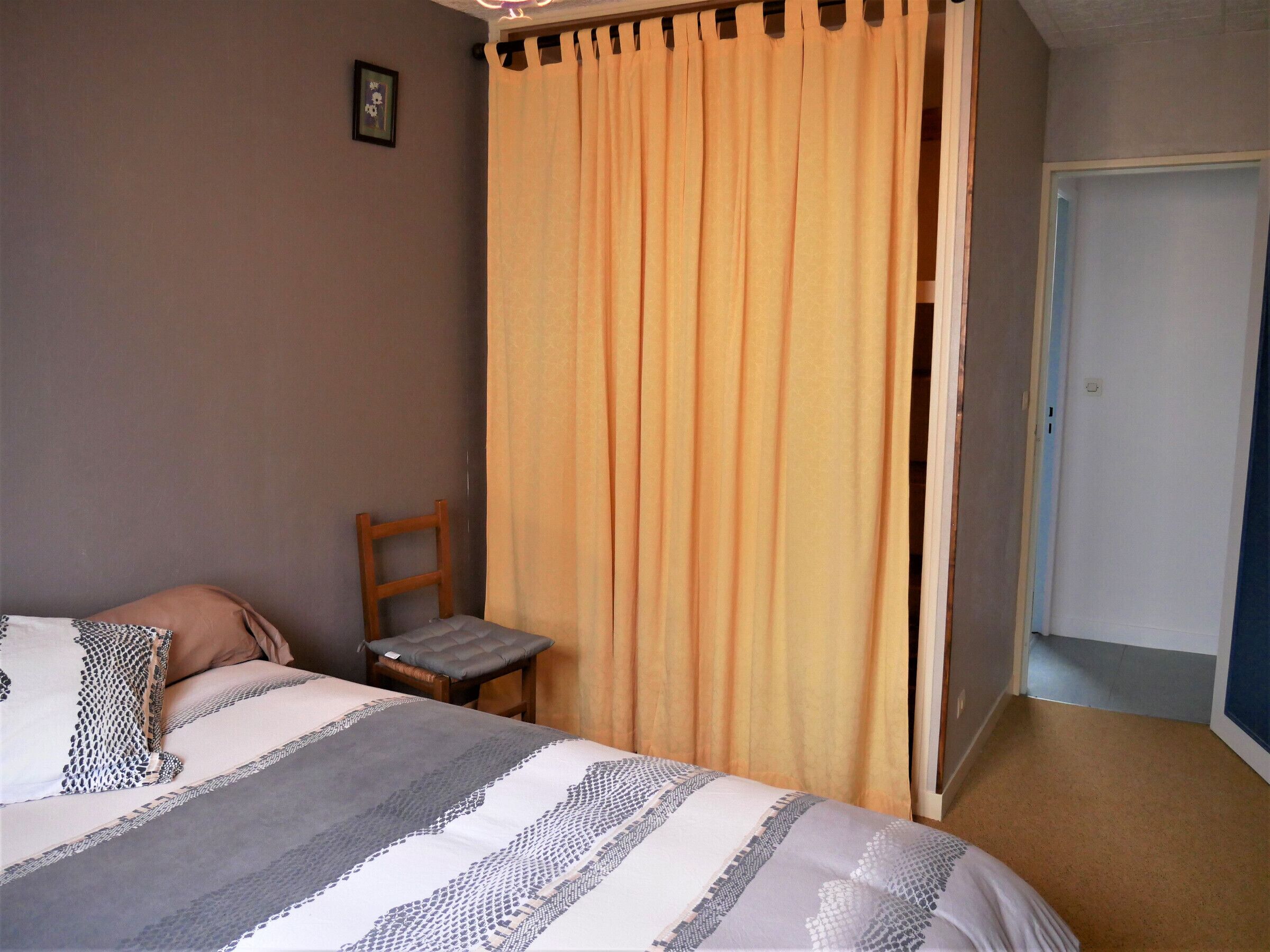 Ein Schlafzimmer mit einem Bett, einem Stuhl und einer Tür.