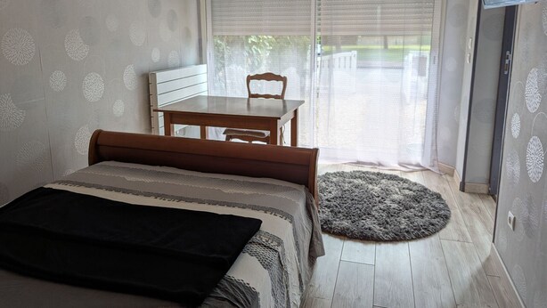 Un dormitorio con cama, una mesa de madera, una silla y un televisor.