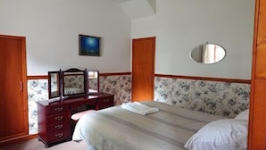 A bedroom with a bed, dresser, mirror, and a painting on the wall. - 4-bed Property in Converted Coach House in Turriff (Turriff)