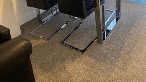 Une salle de conférence avec une table en verre et quatre chaises noires.