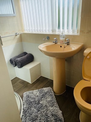 A bathroom with a beige sink, a toilet, a towel rack, and a window with blinds. - The 5 bed House With Spacious Rooms and Lounge (Coventry)