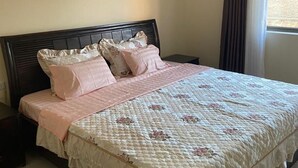 Une chambre à coucher avec un lit, une table de chevet, une fenêtre avec des rideaux et une porte.