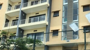 Un immeuble à plusieurs étages doté de balcons, d’une clôture et de quelques éléments de végétation.