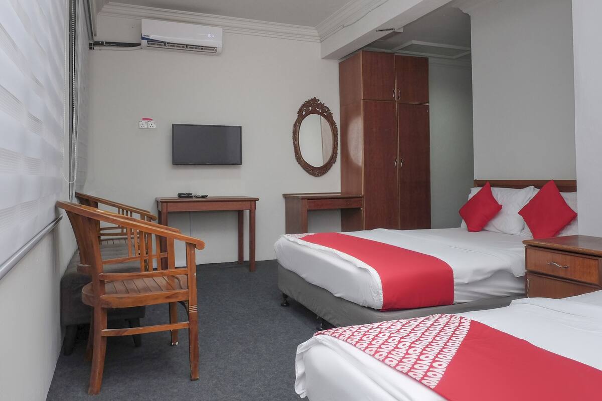 Een hotelkamer met twee bedden, een bureau, een stoel, een televisie en een kledingkast.