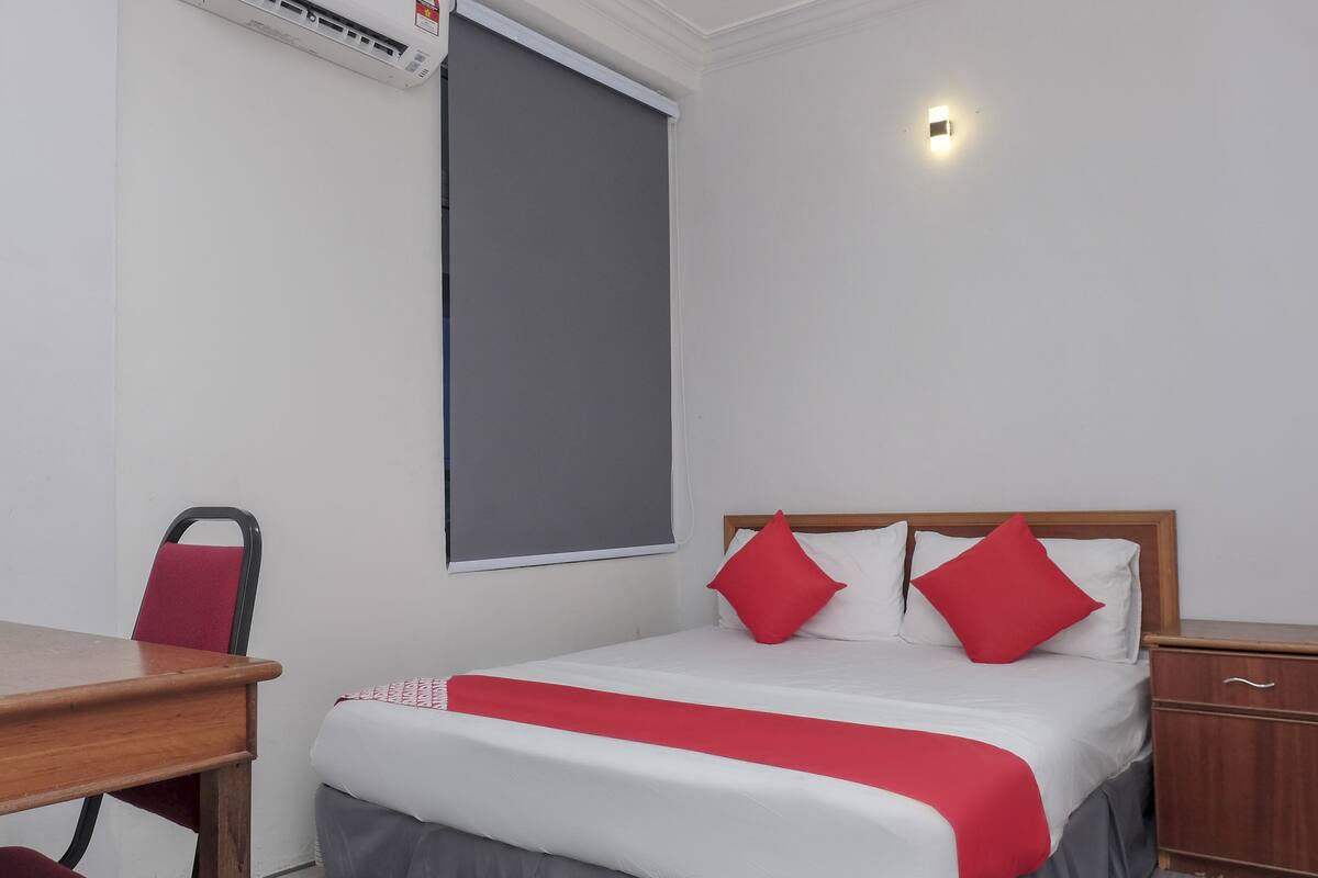 Een netjes ingerichte hotelkamer met een bed, bureau en stoel.