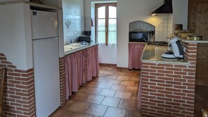 Una cocina con refrigerador, microondas y horno de ladrillo.