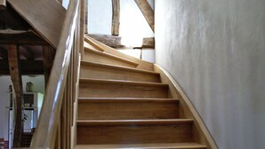 Una escalera de madera con barandilla, que sube a un piso superior.