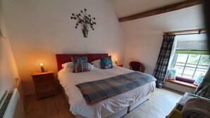Een slaapkamer met een groot bed, een houten hoofdbord, nachtkastjes met lampen, een raam met gordijnen, en een decoratie aan de muur.