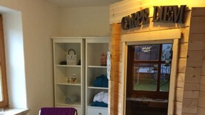 A room with a wooden door labeled "CROFT LEMM," a white chair with a purple cover, and a white cabinet with shelves.