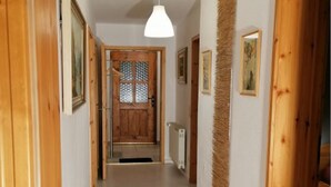 A hallway with wooden doors, a white pendant light, and framed pictures on the walls.