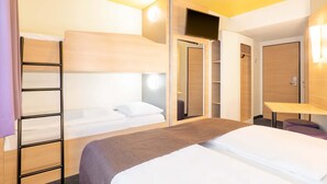 Una habitación de hotel con literas, un escritorio, un armario y un baño.