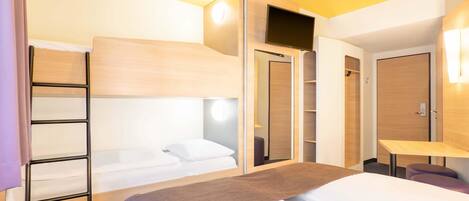 A hotel room with a bunk bed, a desk, a wardrobe, and a bathroom.