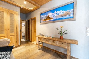 Ein Holzkorridor mit einer Holzbank, einem Blumentopf und einem gerahmten Bild von verschneiter Berglandschaft.