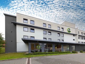 A B&B hotel with a modern design, featuring a flat roof, large windows, and a well-maintained garden area.