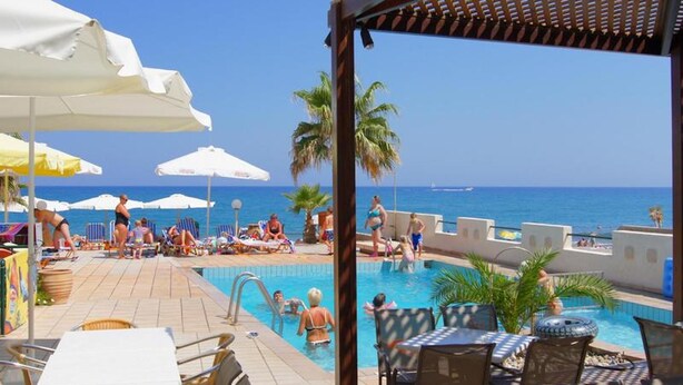 A poolside area with lounge chairs and umbrellas, overlooking a clear blue sea. - Apartment for 4 Persons, Swimming Pool, Near the Beach (Rethymno)