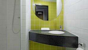A bathroom with a shower, a sink, and a mirror. - B&B Hotel Frankfurt City-Ost (Frankfurt)