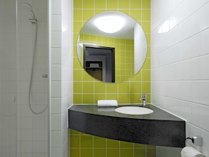 A bathroom with a shower, a sink, and a mirror. - B&B Hotel Frankfurt City-Ost (Frankfurt)
