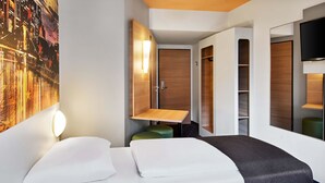 A modern hotel room with a bed, a bedside table, a mirror, a wall-mounted TV, and a large window. - B&B Hotel Frankfurt City-Ost (Frankfurt)