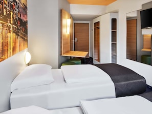 A modern hotel room with a bed, a bedside table, a mirror, a wall-mounted TV, and a large window. - B&B Hotel Frankfurt City-Ost (Frankfurt)