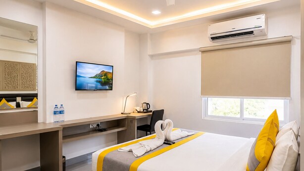 Quarto de hotel moderno com cama, escrivaninha e televisão de tela plana.