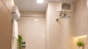 Uma casa de banho moderna com chuveiro, sanita e lavatório.