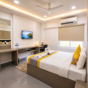 A hotel room with a bed, desk, chair, television, air conditioning unit, and a window. - Room-la Riviera Suites Premium Stay in (Hyderabad)