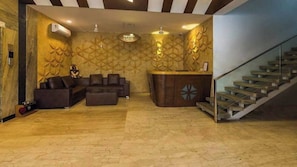 Eine großzügige Lobby mit einer Rezeption, einer Sitzecke und einer Treppe.