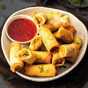 A plate of spring rolls with a side of dipping sauce. - Room-la Riviera Suites Premium Stay in (Hyderabad)