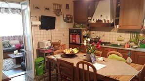 A cozy kitchen with a dining table, chairs, a TV mounted on the wall, and various kitchen items.
