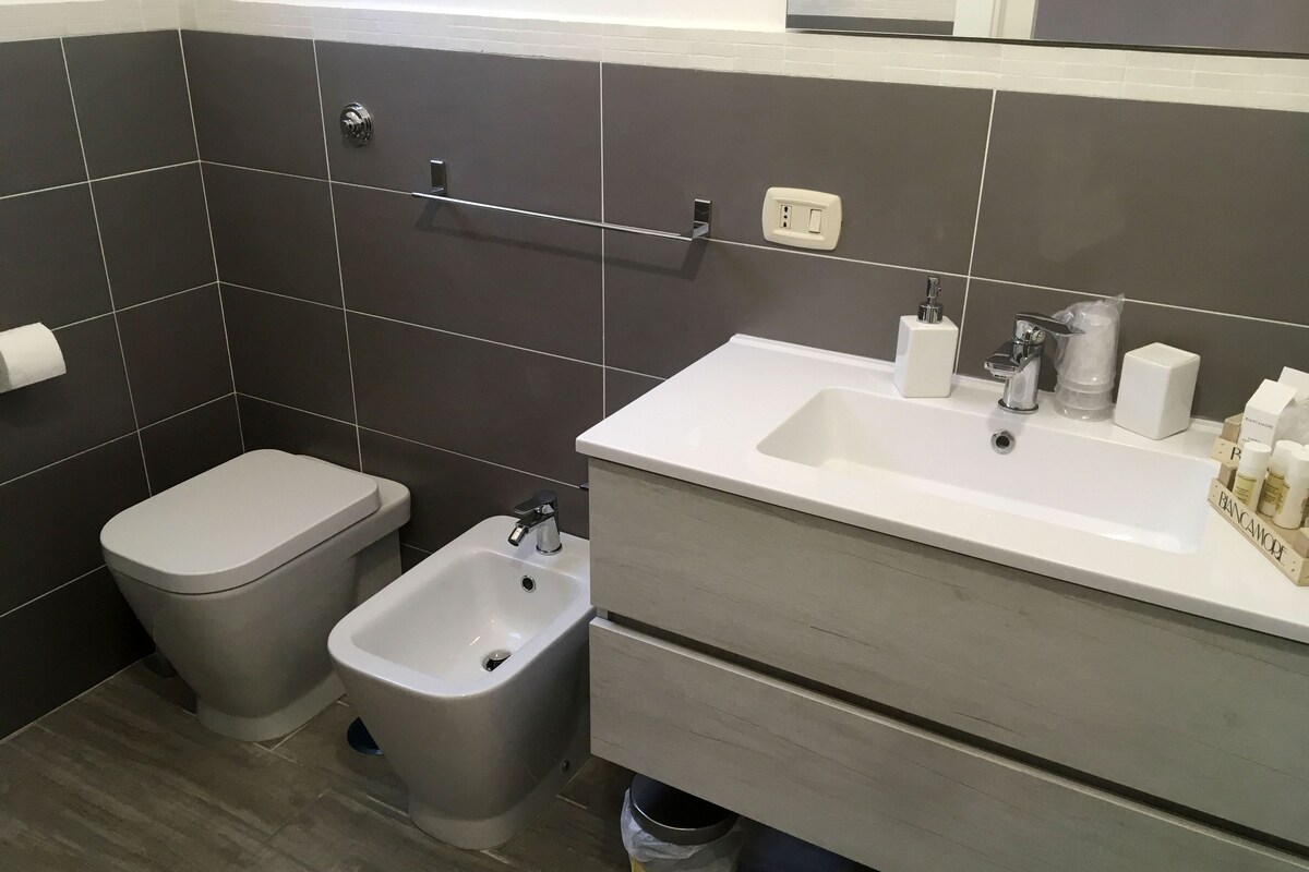 A modern bathroom with a bidet, toilet, and sink.