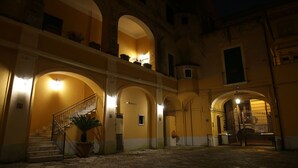 A courtyard with a staircase, potted plants, and a gated entrance at night.