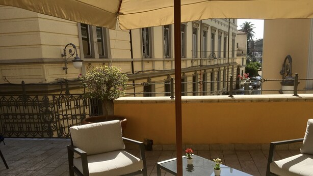 An outdoor seating area with two chairs and a table, a potted plant, and a view of a building with balconies. - Palazzo Benucci - Residenza di Charme (Santa Maria Capua Vetere)
