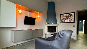 En moderne stue med en grå sofa, et ophængt fjernsyn, en pejs og et billede på væggen.