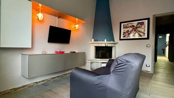 A modern living room with a grey sofa, a mounted TV, a fireplace, and a painting on the wall.