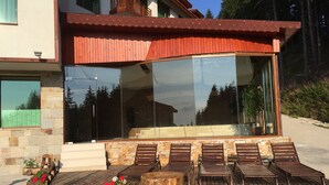 A modern house with a large glass window, wooden deck, and outdoor seating area. - 2 Bedroom, 2 Showeroom Villa Suitable for a Family Skication and Remote Working (Smolyan)