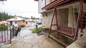 A stone-paved outdoor area with a wooden swing set, a metal railing, and a view of neighboring houses. - 2 Bedroom, 2 Showeroom Villa Suitable for a Family Skication and Remote Working (Smolyan)
