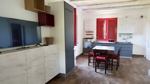 A compact kitchen with a dining area, a TV, and a red door. - Agricontura: House of Lemons with shared swimming pool and breakfast room (Contura)