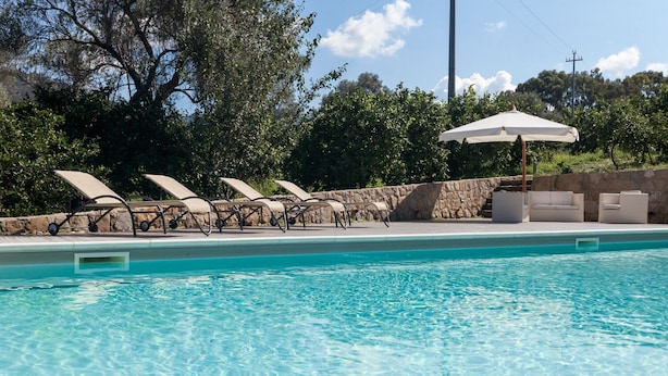 A swimming pool with clear blue water, surrounded by lounge chairs and a stone wall. - Agricontura: House of Lemons with shared swimming pool and breakfast room (Contura)