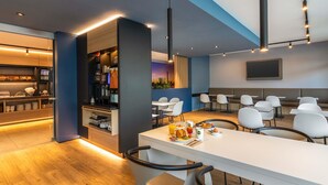 Een moderne hotel lobby met een bar, zitplaatsen en een flatscreen televisie.