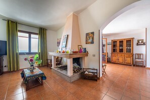 A living room with a fireplace, a dining table with a vase of flowers, and a television.