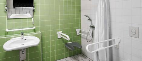 A bathroom with green tiled walls, a white sink, a toilet, and a shower with a white curtain.
